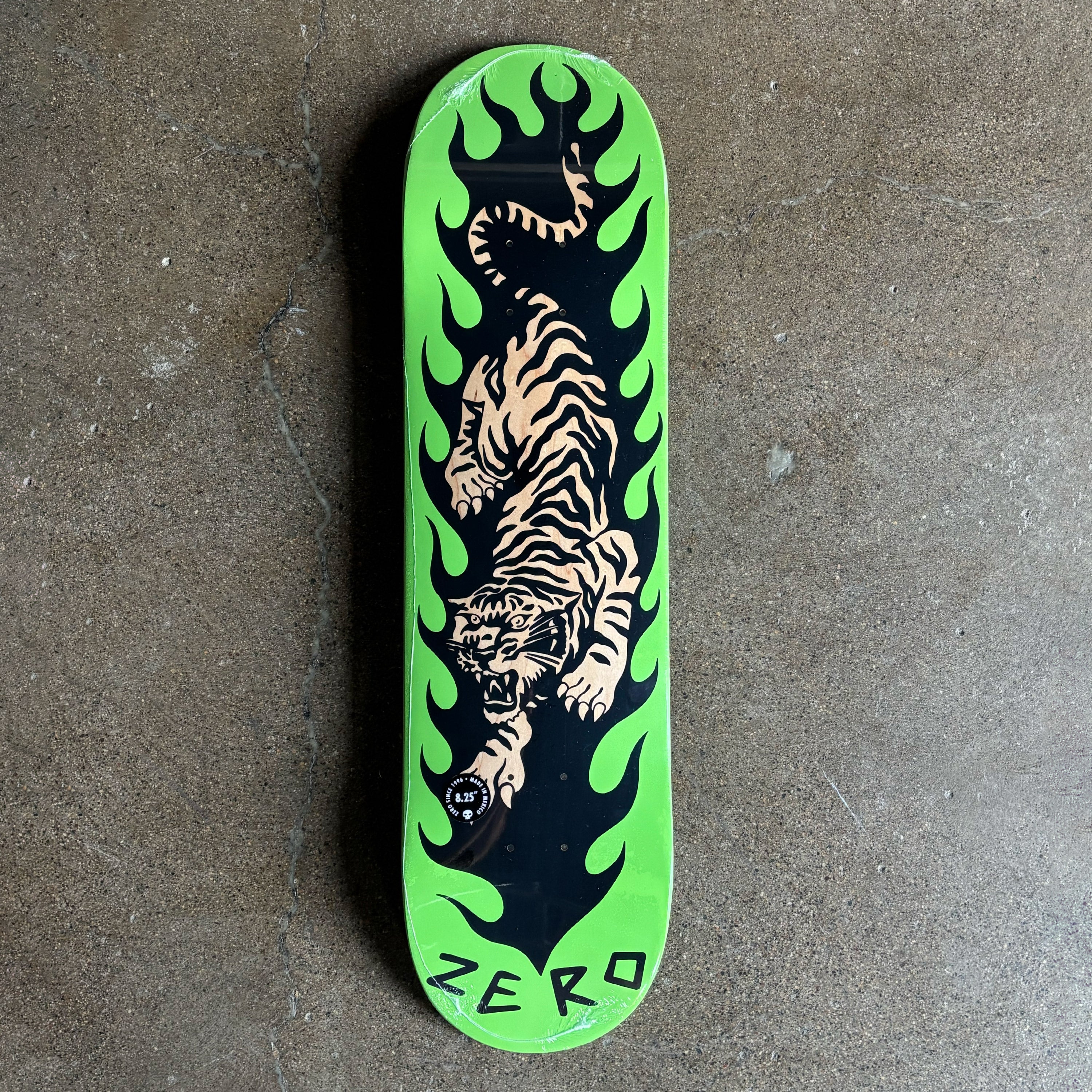 Skateboard deck with a tiger and flame design on a green background.
